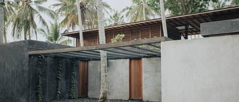 A modern building with a concrete facade, wooden doors, and a covered outdoor area.