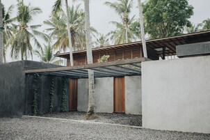 Um edifício moderno com fachada de concreto, portas de madeira e área externa coberta.