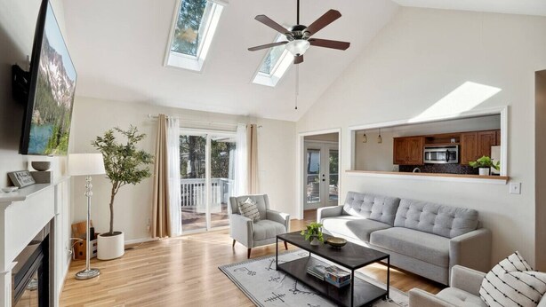 A spacious living room with a fireplace, a ceiling fan, a large grey sofa, a coffee table, and a sliding glass door leading to a balcony. - Hialeah Hole in One Golf House (Pinehurst)