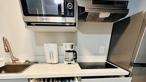Une cuisine équipée d’un four à micro-ondes, d’une machine à café et d’un réfrigérateur en acier inoxydable.