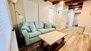 A living room with a light green sofa, a wooden coffee table, and a wooden floor.