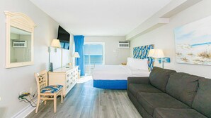 Een slaapkamer met een bed, een bank, een bureau met stoel, een dressoir, een spiegel en kunstwerken aan de muur.