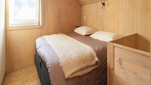 Un dormitorio pequeño y acogedor con una cama individual, un aparador de madera y una ventana con cortinas.