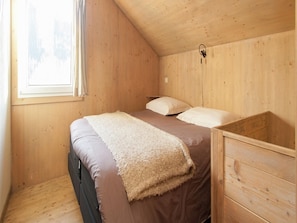 Una camera da letto accogliente e intima con un letto singolo, una cassettiera in legno e una finestra con tende.