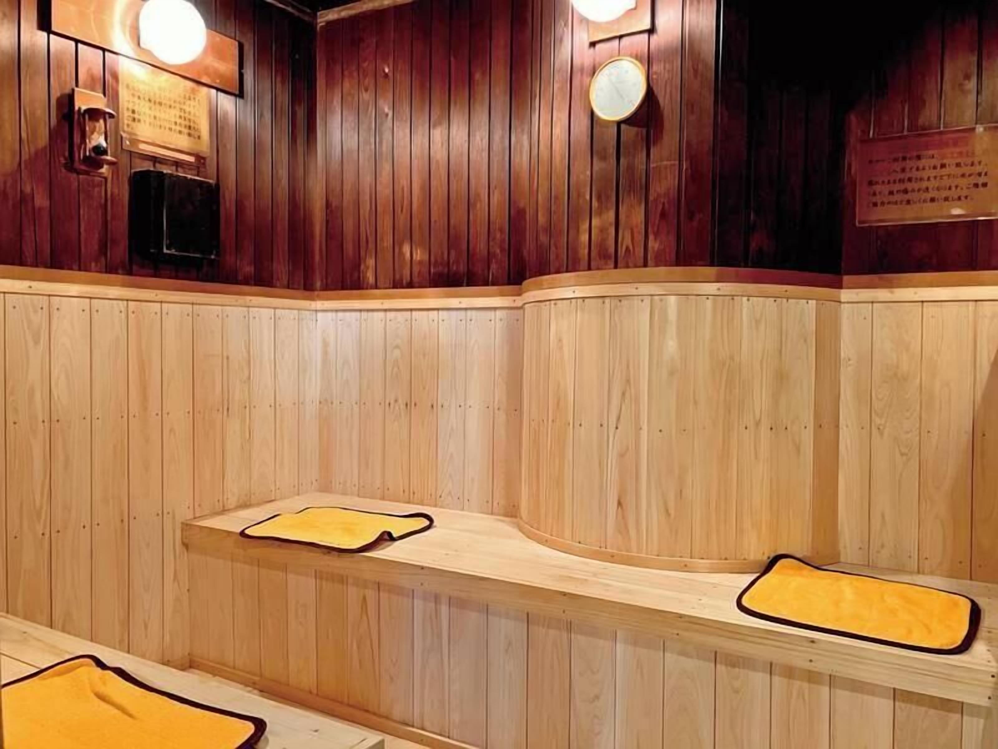 A wooden sauna with benches and wall-mounted lights.
