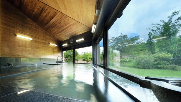 A modern indoor swimming pool with a wooden ceiling and large windows offering a view of greenery outside. - Hotel Tetora Resort Sendai Iwanuma (Iwanuma)