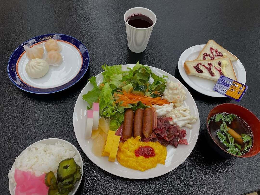 Een tafel met verschillende gerechten, waaronder dumplings, salade, worst en rijst.