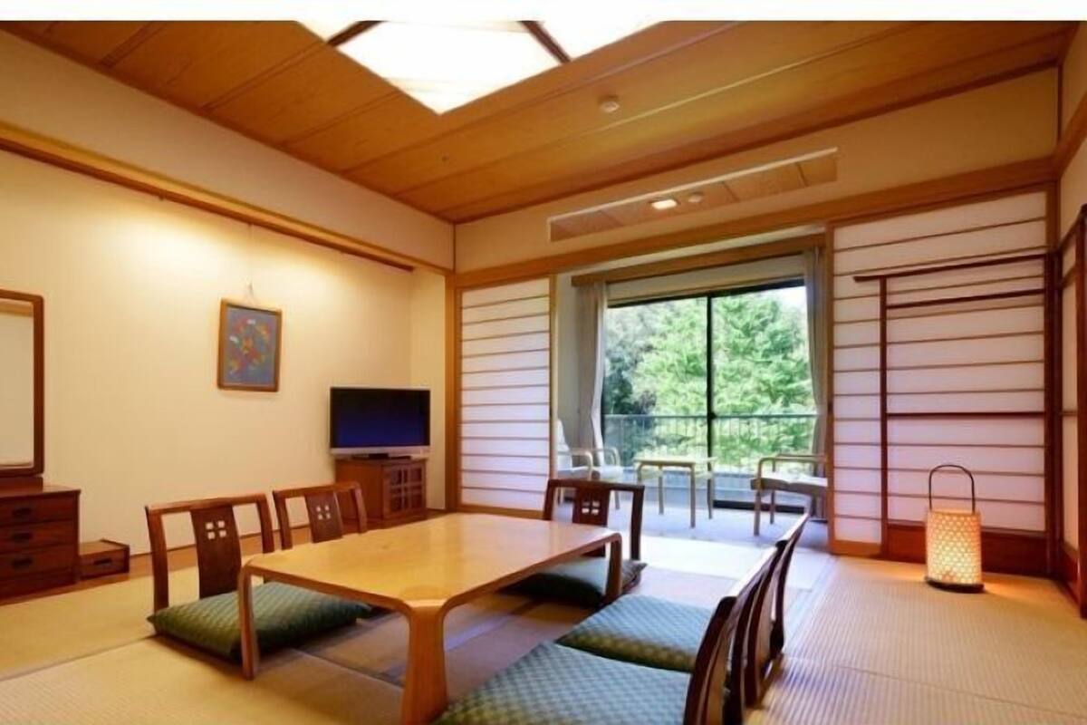 Et traditionelt japansk værelse med tatamimåtter, et lavt træbord og et fjernsyn.