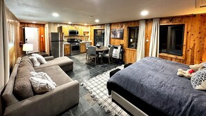 A modern, well-lit room with a sofa, a bed, a dining table, and a kitchen area. - Studio style cabin in Twin Bridges with Mountain View’s near Sierra Ski Resorts (Twin Bridges)