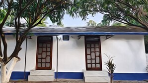 A white building with blue trim and two windows with brown frames. - The Corbett Canopy Home Stay (Kaladhungi)
