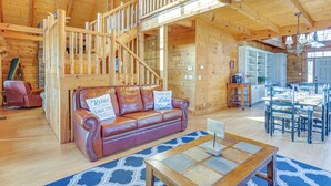 L’intérieur d’un chalet en bois, avec un canapé en cuir, une table à manger et un escalier.