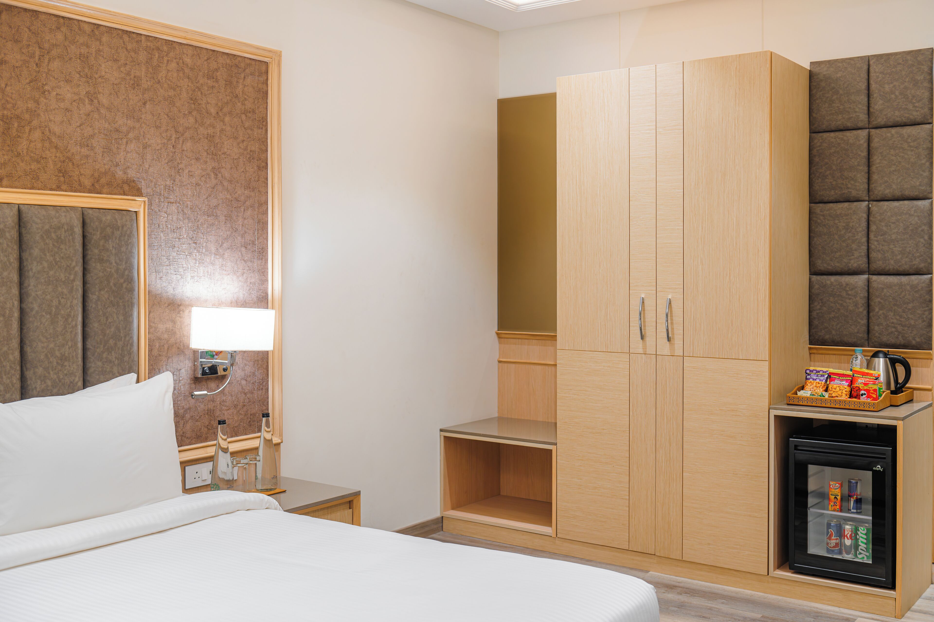 Une chambre d’hôtel équipée d’un lit, d’un minibar, d’une armoire et d’un petit réfrigérateur.