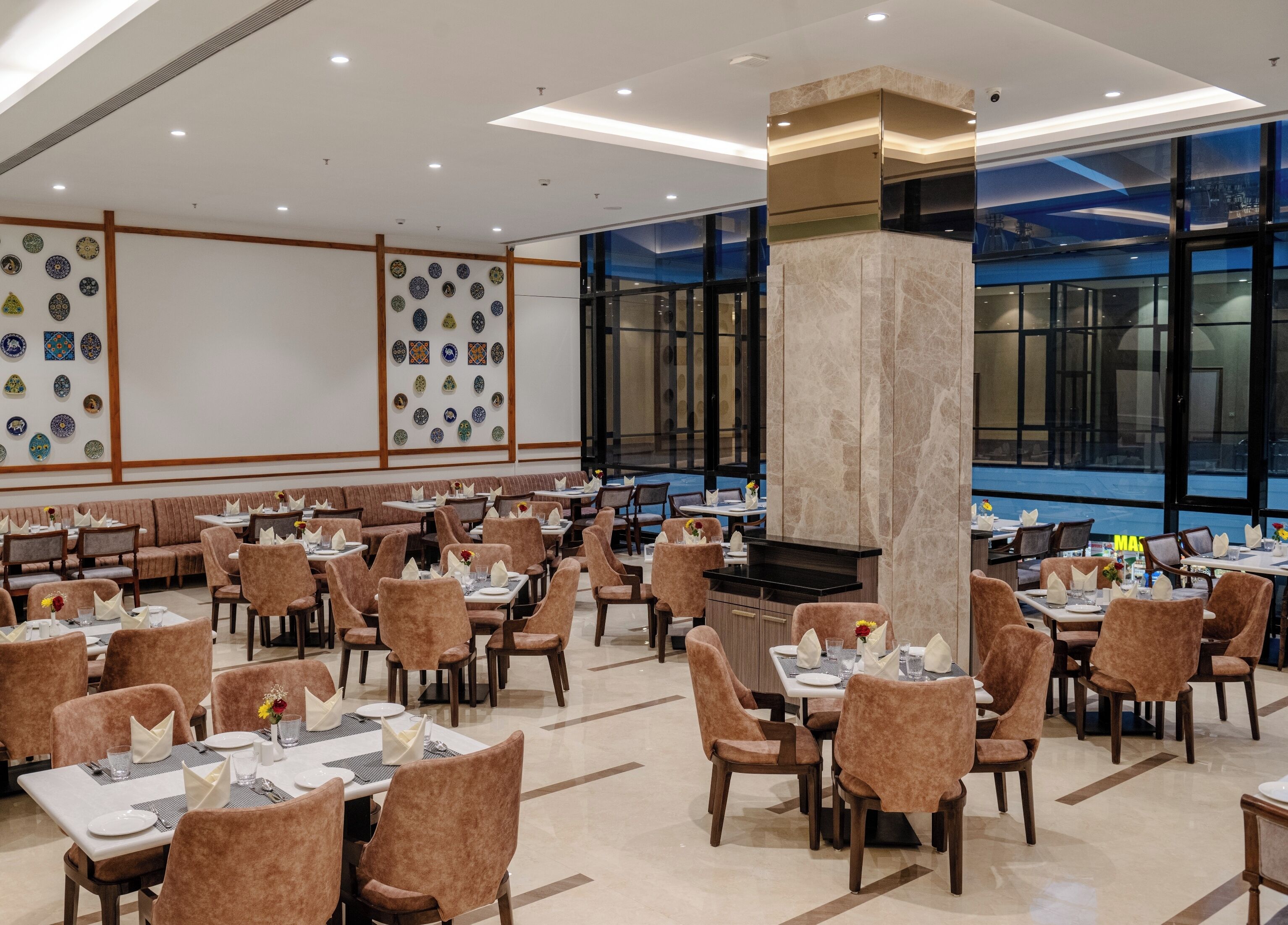 A spacious restaurant with multiple dining areas, a central fireplace, and large windows offering views.