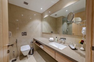 Un baño moderno con un espejo grande, dos lavamanos, un inodoro y una ducha.