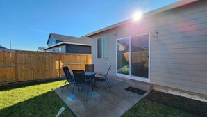 A backyard with a patio, a wooden fence, and a house with a large sliding glass door. - Modern Salem Property (Salem)