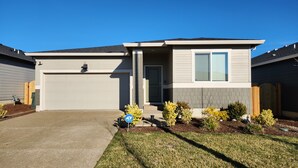 A two-story house with a garage, a front door, and a small front yard with shrubs. - Modern Salem Property (Salem)