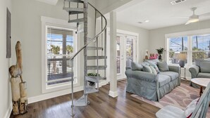 A spacious living room with a spiral staircase, large windows, and a view of the outdoors.
