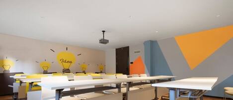 A conference room with white tables, yellow chairs, and a whiteboard.
