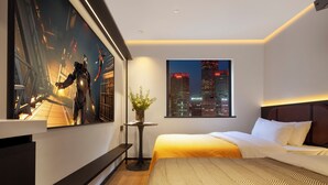 A modern hotel room with a large bed, a cityscape view, a framed artwork, and a small table with a vase.