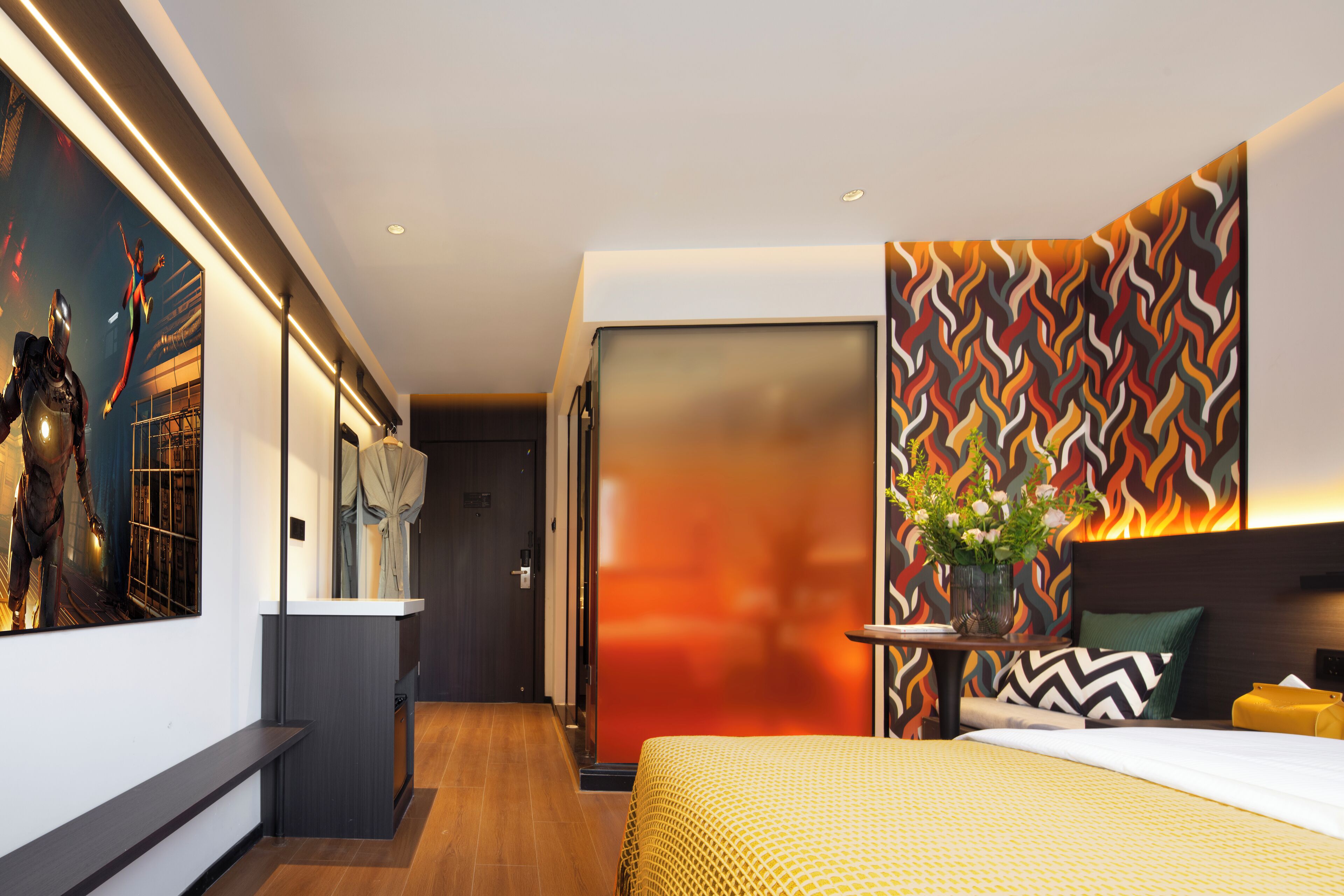 Een moderne hotelkamer met een groot bed, een nachtkastje met een bloevas, een muur met een geometrisch patroon, en een groot schilderij aan de linker muur.