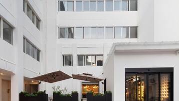 A modern building with a courtyard featuring outdoor seating, planters, and a glass entrance.