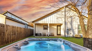 A backyard with a hot tub, wooden fence, and a house with a covered patio. - The Cacti House - Hot Tub, Game Room, Cactus Mural, Minutes from Downtown Dallas (Dallas)