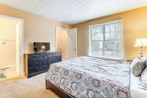 Quarto com cama, cômoda e janela com persianas.