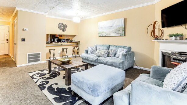 A living room with a sofa, ottoman, coffee table, and a fireplace. - 8 Mi to Stone Mountain: Quiet Getaway w/ Deck (Lithonia)