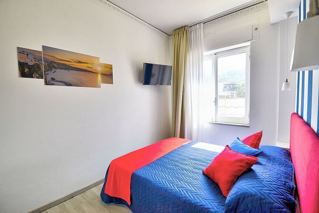 A bedroom with a bed, a TV, and two pictures on the wall.