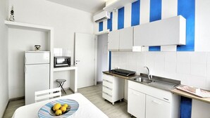 A compact kitchen with white cabinets, a microwave, a sink, and a small dining area with a table and a bowl of lemons. - Appartamento Denise: A bright and cheerful apartment immersed in a splendid landscape, in the heart of a wonderful little town, with Free WI-FI. (Massa Lubrense)