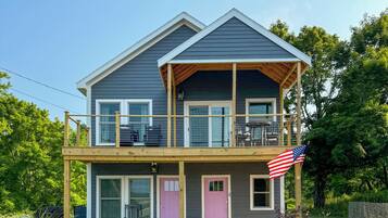Une maison à deux étages avec un balcon, un porche à l’avant et un drapeau.