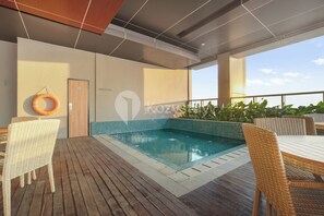 A rooftop pool area with wicker furniture, a lifebuoy, and a door labeled "Kozva". - Kiyo by Kozystay - Kemayoran (Jakarta)