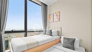 A modern hotel room with a large window, a bed with white bedding, and two abstract art pieces on the wall. - Kiyo by Kozystay - Kemayoran (Jakarta)