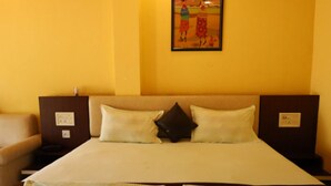 A hotel room with a large bed, two pillows, a nightstand, a lamp, and a painting on the wall.