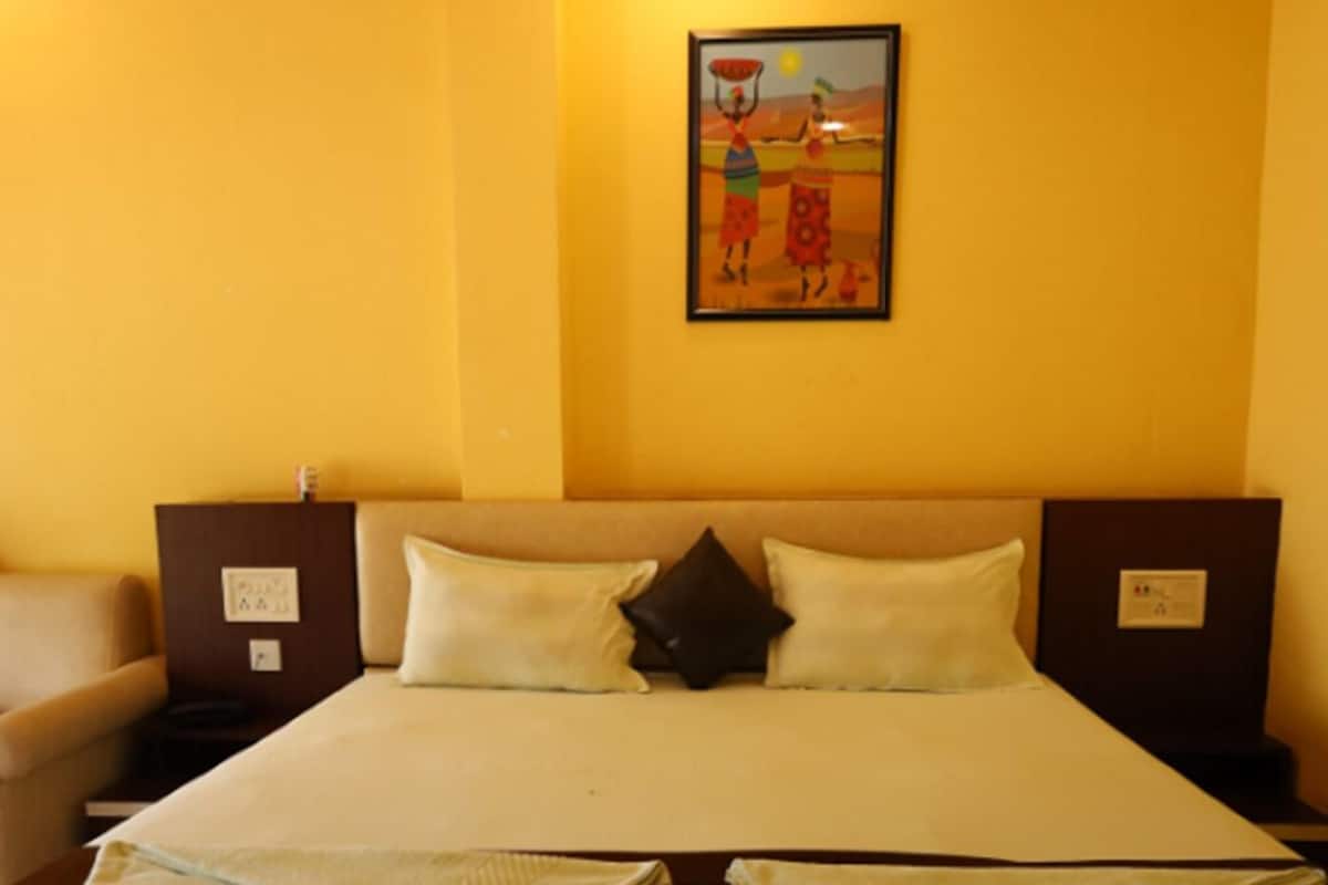 A hotel room with a large bed, two pillows, a nightstand, a lamp, and a painting on the wall.