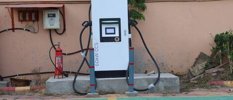 A 60kW CCS electric vehicle charging station with a control panel, connected to a wall-mounted electrical box and hoses.