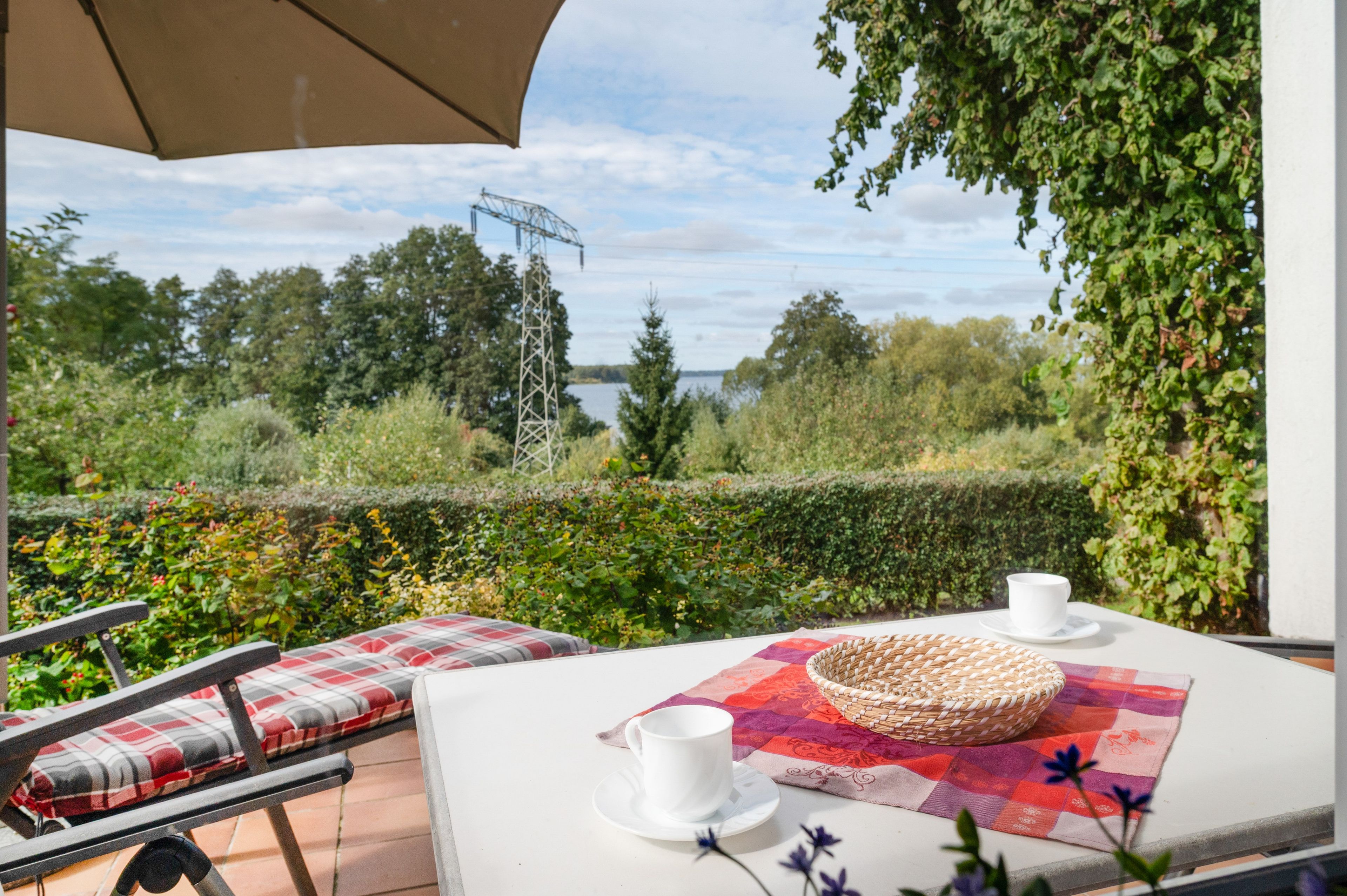An outdoor seating area with a table, chairs, and a view of a lake and trees.