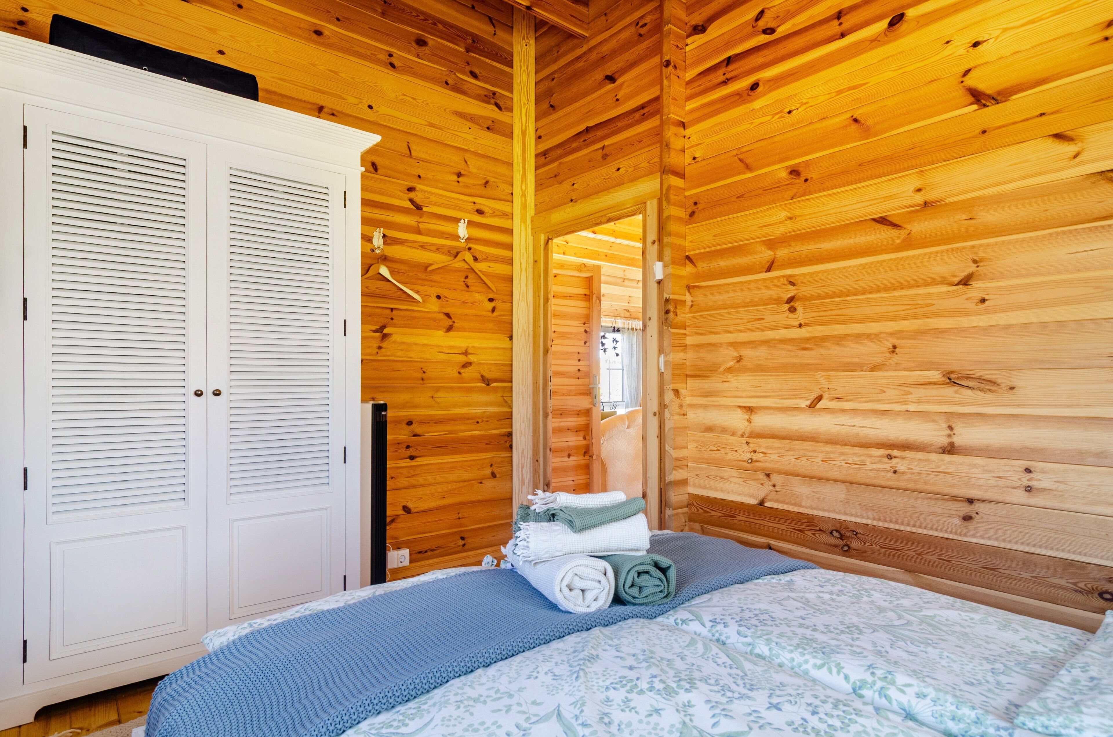 A wooden-paneled room with a bed, a wardrobe, and a mirror.