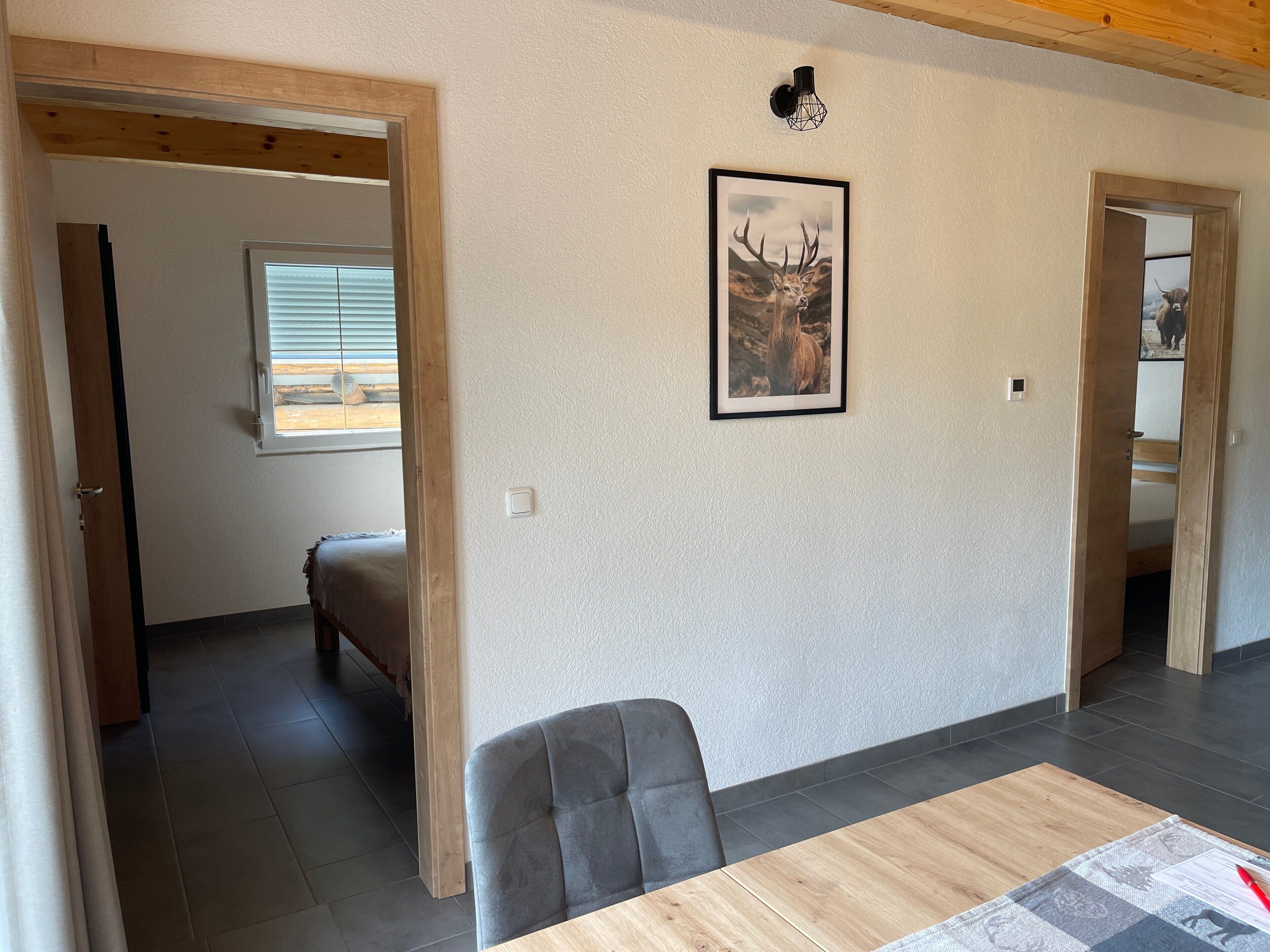 A room with a dining table, a framed deer picture, and a window with blinds.