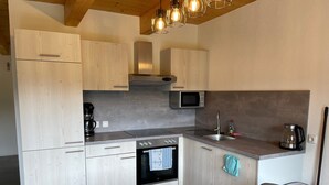 A modern kitchen with wooden cabinets, a built-in oven, a microwave, and a coffee maker.