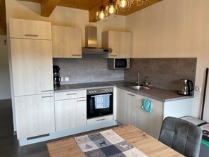 Eine moderne Küche mit Holzausstattung, einem Backofen, einer Mikrowelle und einer Kaffeemaschine.