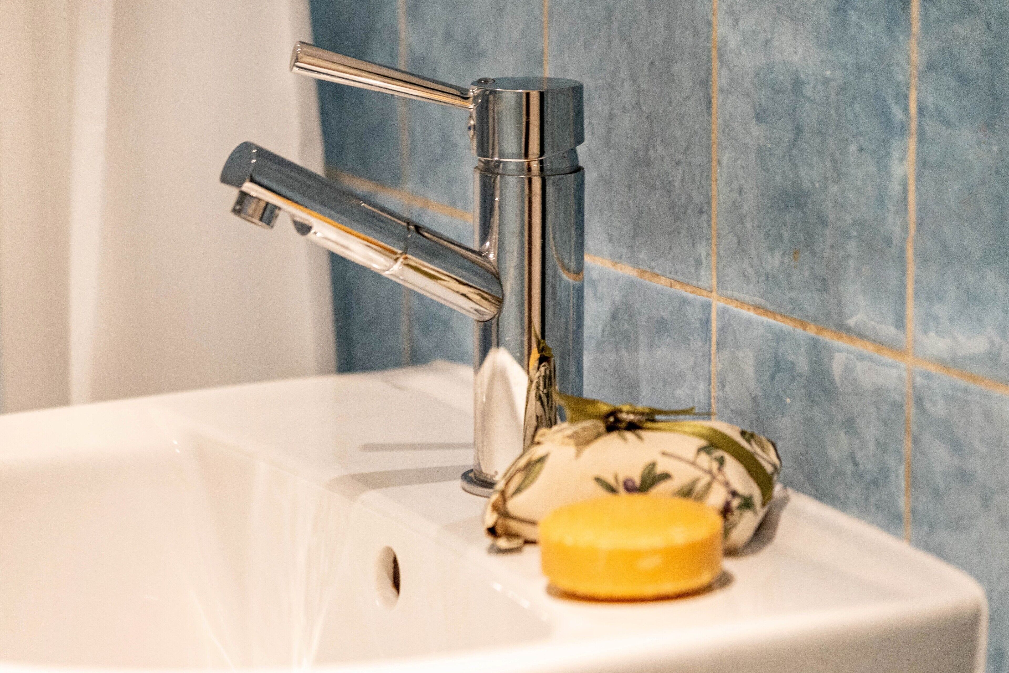 A bathroom sink with a chrome faucet, a soap bar, and a decorative item on the counter.