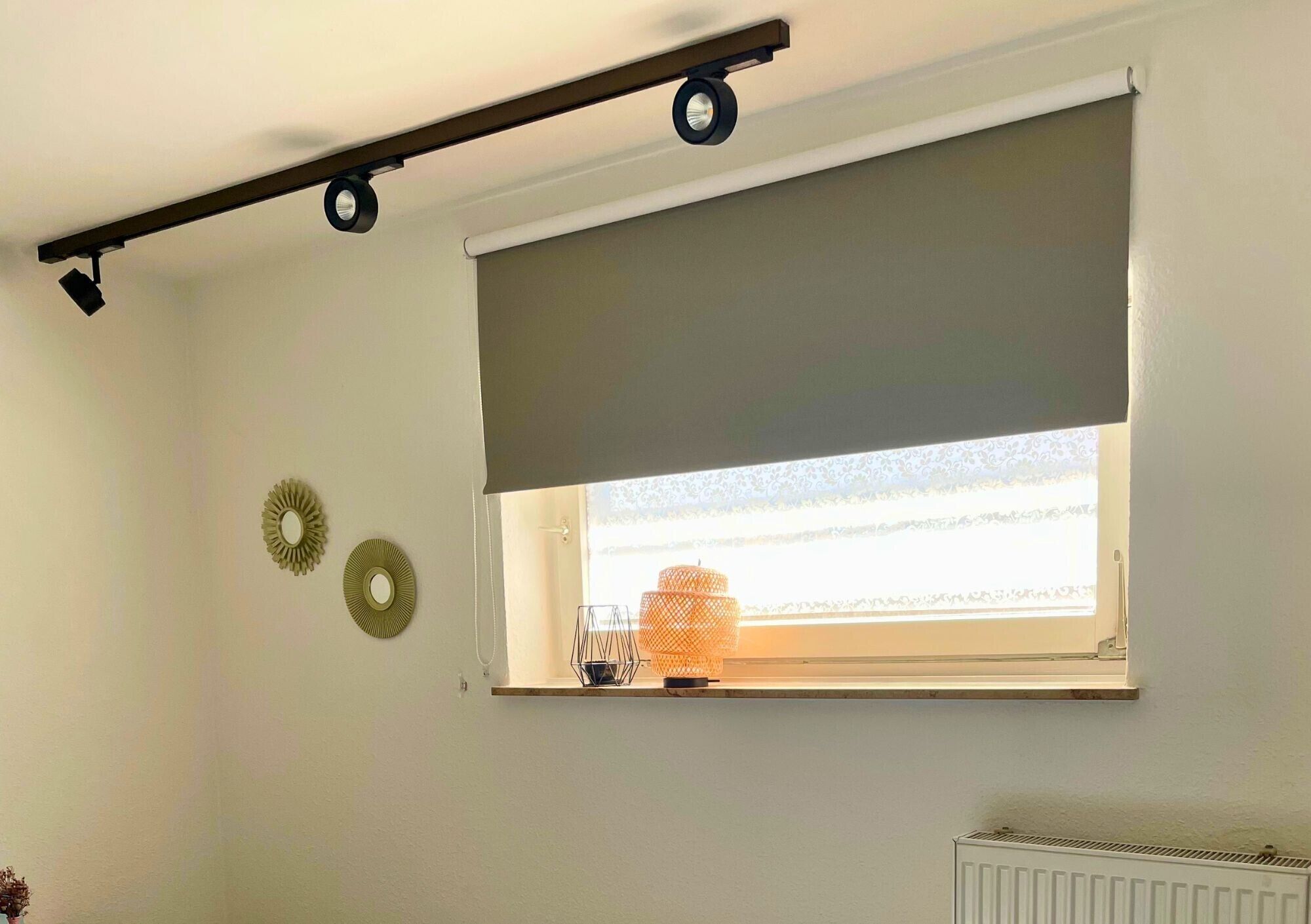 Ein Zimmer mit Fenster, Heizkörper und zwei Wandleuchten.