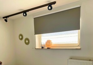 A room with a window, a radiator, and two wall-mounted light fixtures. - 'Kleines, Feines' Holiday Apartment with Wi-Fi (Dortmund)