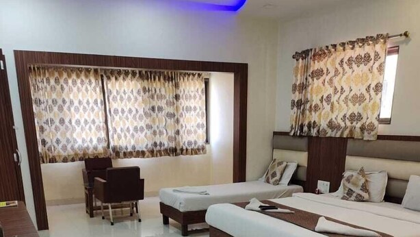 A modern hotel room with a large bed, a desk, and a chair. - Hotel Golden Palms (Mumbai)
