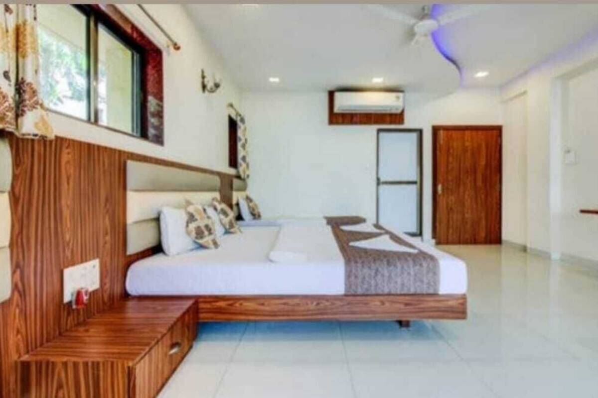 A bedroom with a wooden bed frame, a bedside table, and a window with curtains.