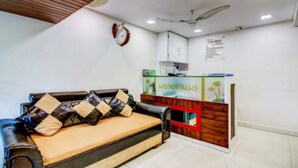 A reception area with a sofa and a wooden counter displaying the name 'Golden Palms'. - Hotel Golden Palms (Mumbai)