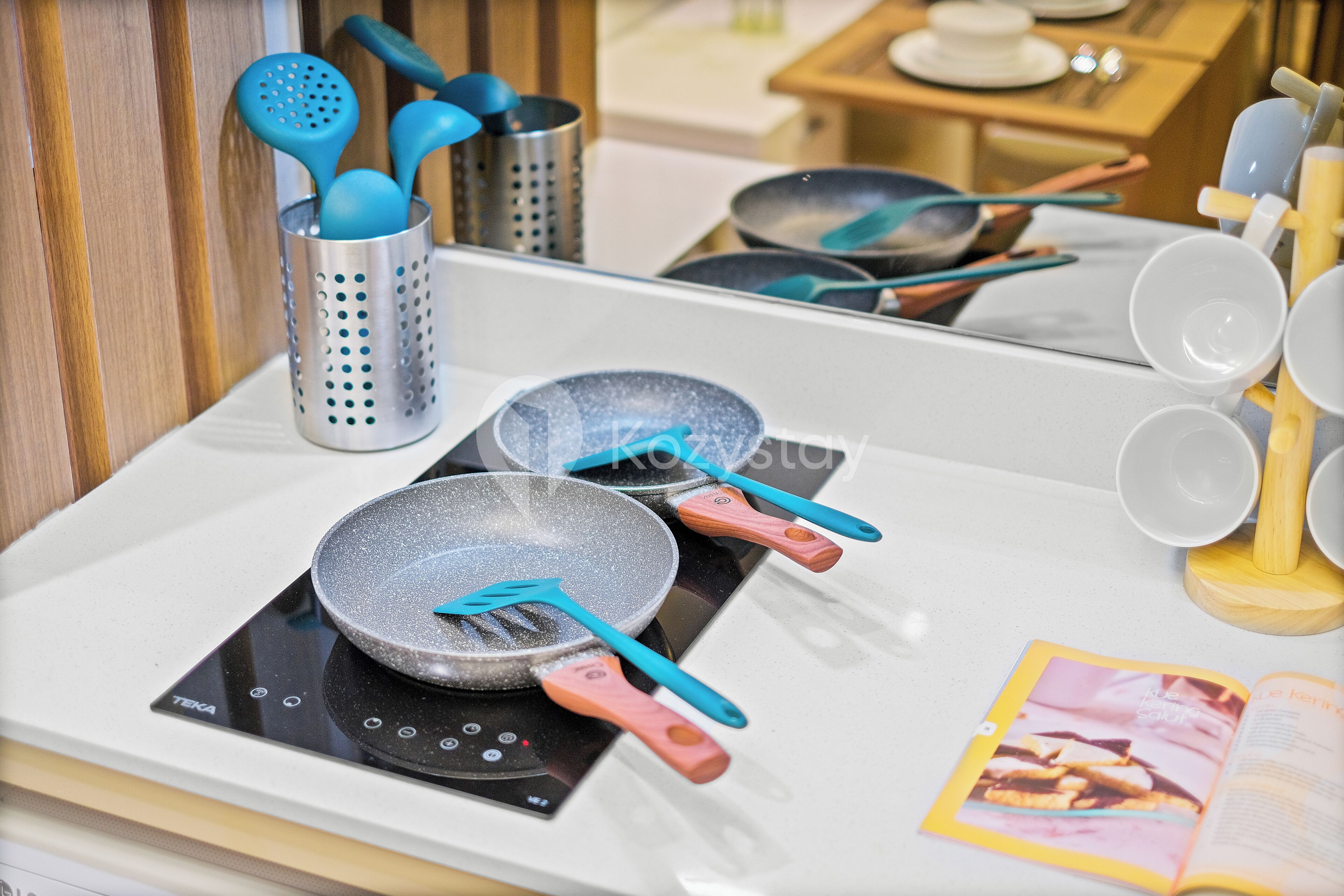 A kitchen counter with a frying pan, spatulas, and a cookbook.