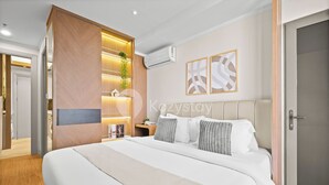 A modern bedroom with a large bed, a wooden wardrobe, a bedside table with a lamp, and two abstract wall art pieces. - Mina by Kozystay - Kemayoran (Jakarta)