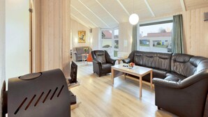 A spacious living room with a sofa, chairs, a coffee table, and a television. - 4 Star Holiday Home in Ottendorf (Otterndorf)